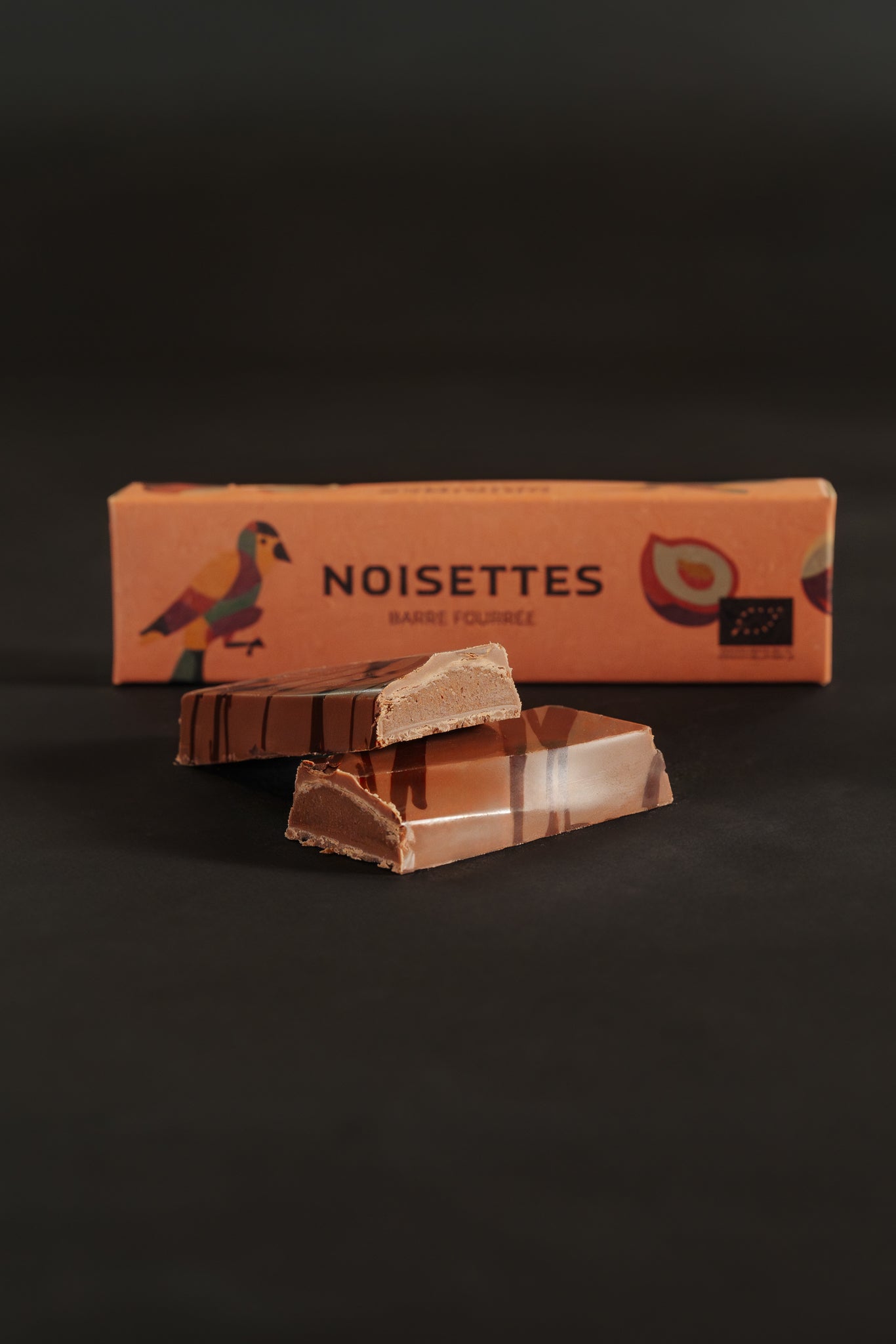 Barre chocolatée fourrée au noisettes avec un emballage marqué 'Noisettes', sur fond noir.