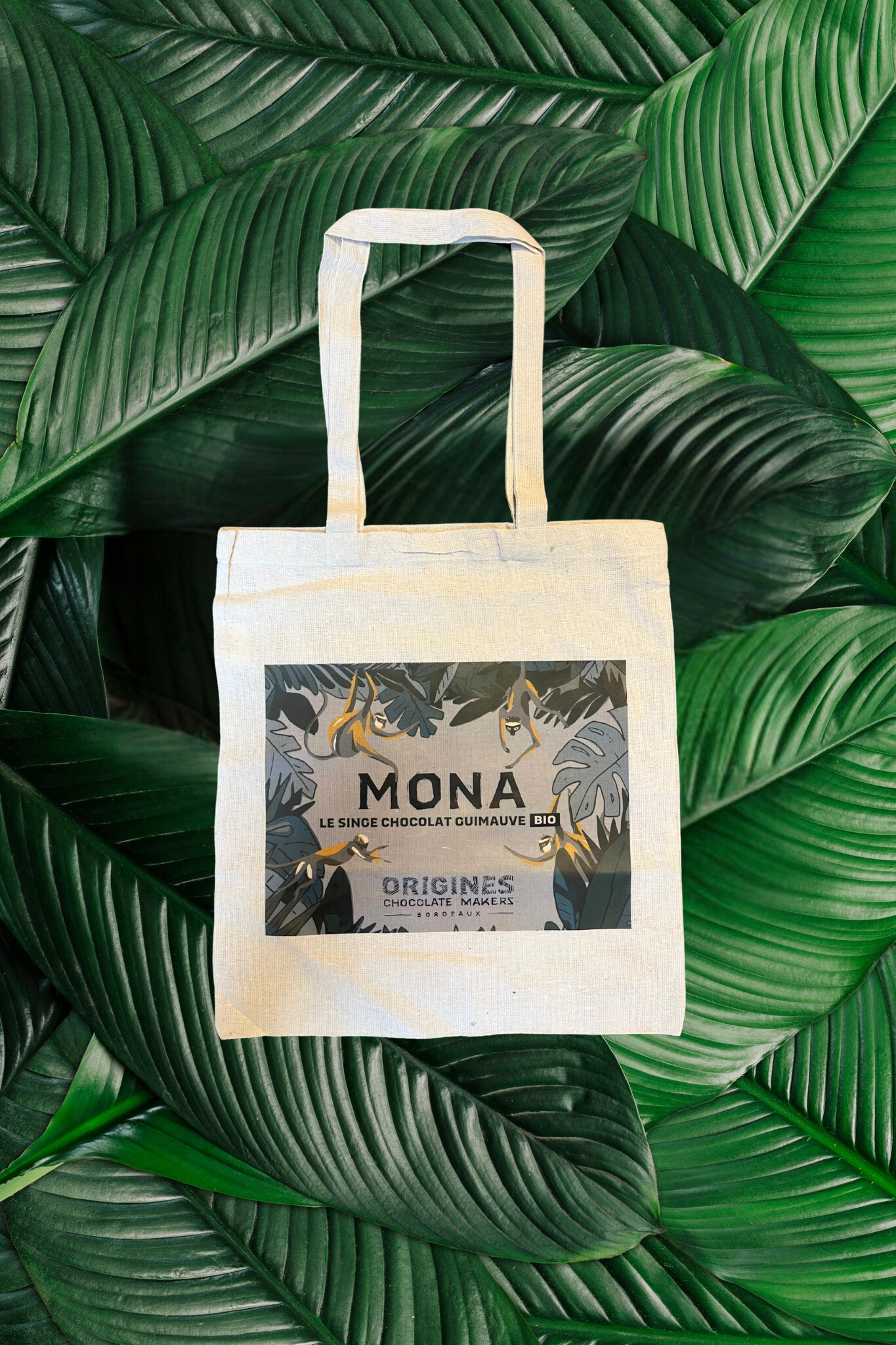 Élégant tote bag en coton biologique, illustré d’un design jungle exotique avec des singes espiègles et des feuillages luxuriants. Parfait pour les amateurs de chocolat et de nature, ce sac réutilisable allie style et engagement écologique."