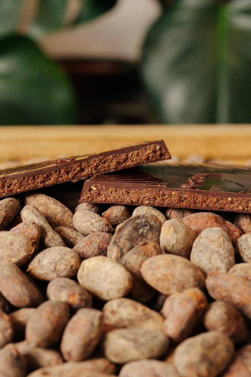 Tablette de chocolat fourré à la pistache sur un fond de fèves de cacao.