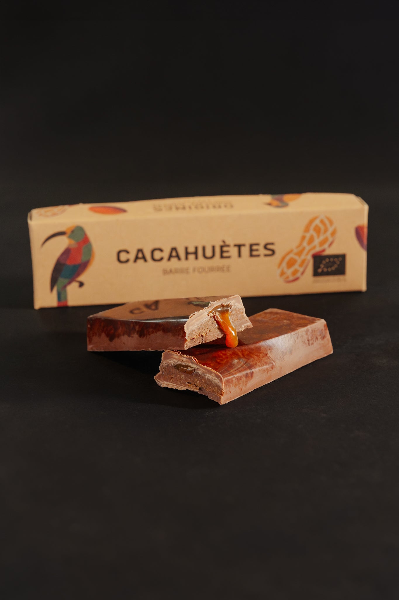Barre chocolatée fourrée au caramel avec un emballage marqué 'Cacahuètes', sur fond noir.